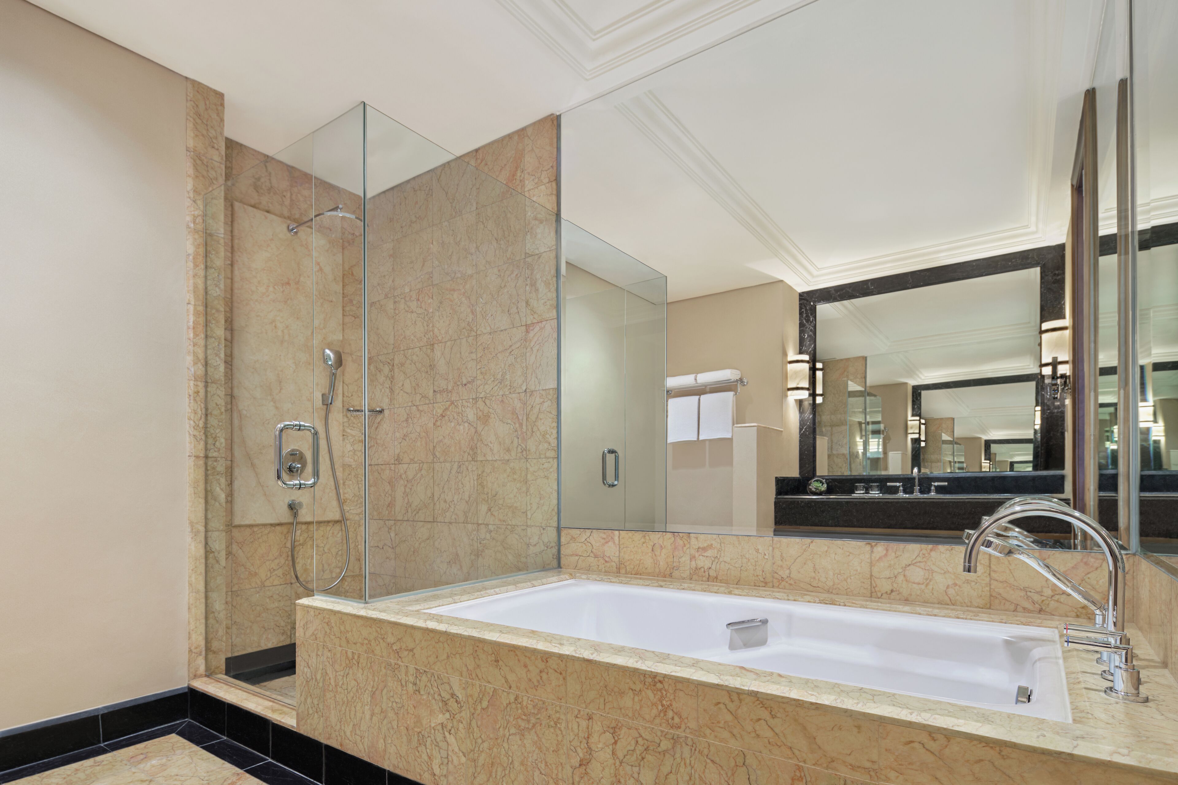 Une salle de bain moderne avec un grand miroir, une baignoire et une douche.
