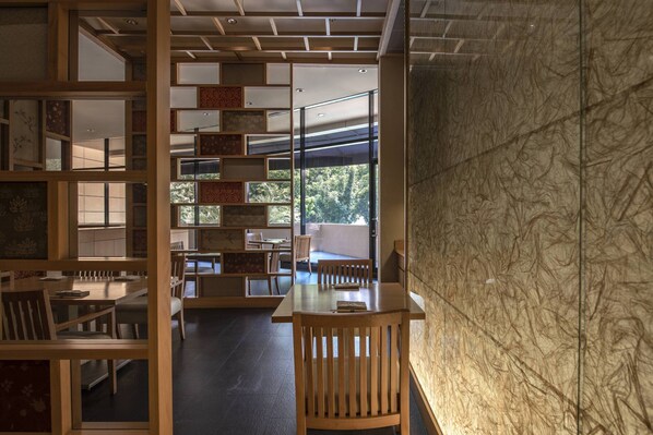 Un interior moderno con muebles de madera, una división de vidrio y vistas a la vegetación exterior.