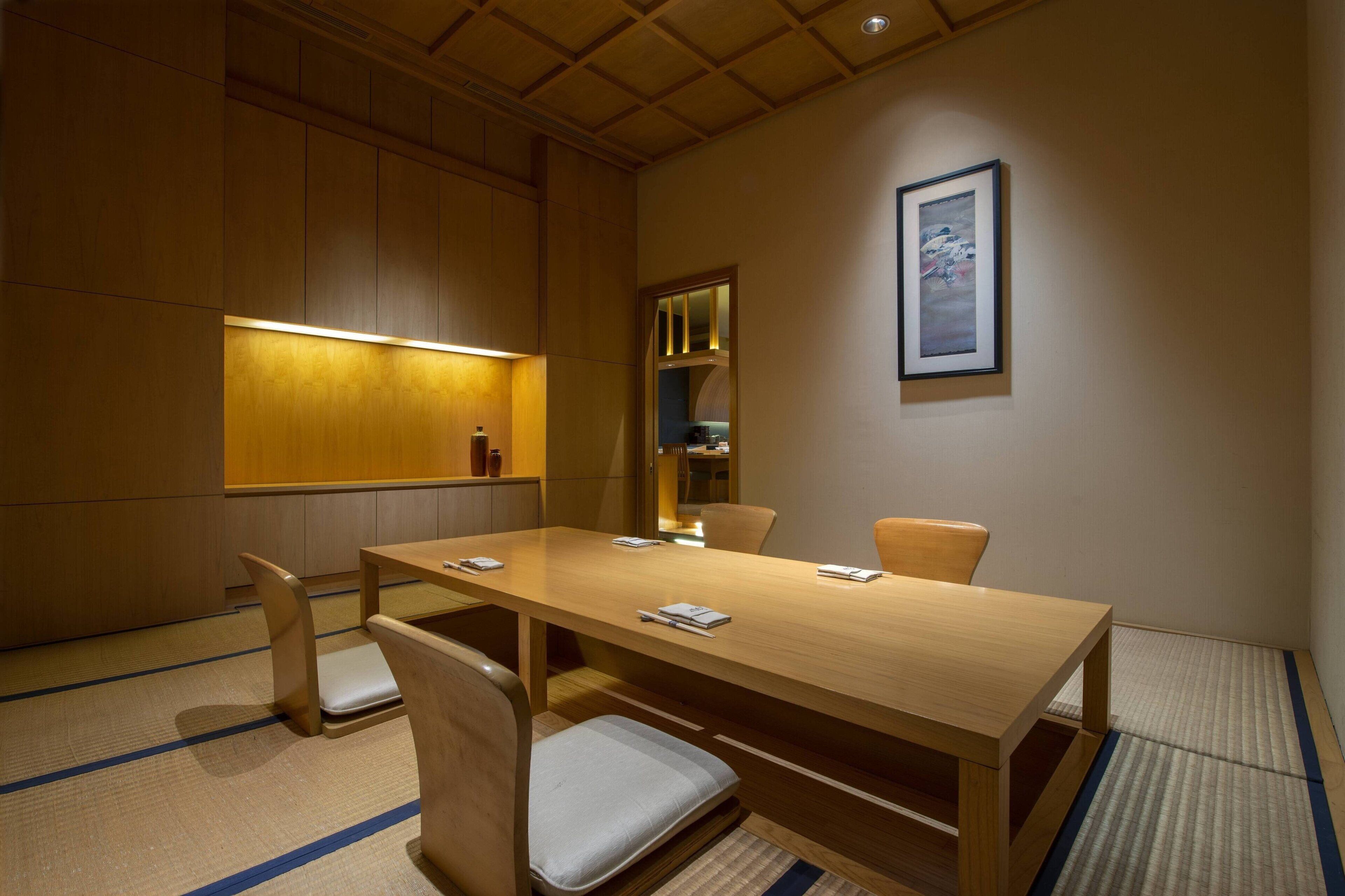 Un salón de conferencias con una larga mesa de madera, cuatro sillas y un cuadro enmarcado en la pared.