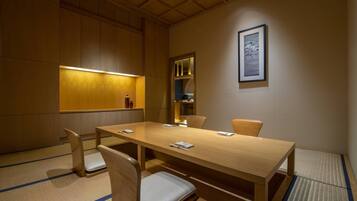 Un salón de conferencias con una larga mesa de madera, cuatro sillas y un cuadro enmarcado en la pared.