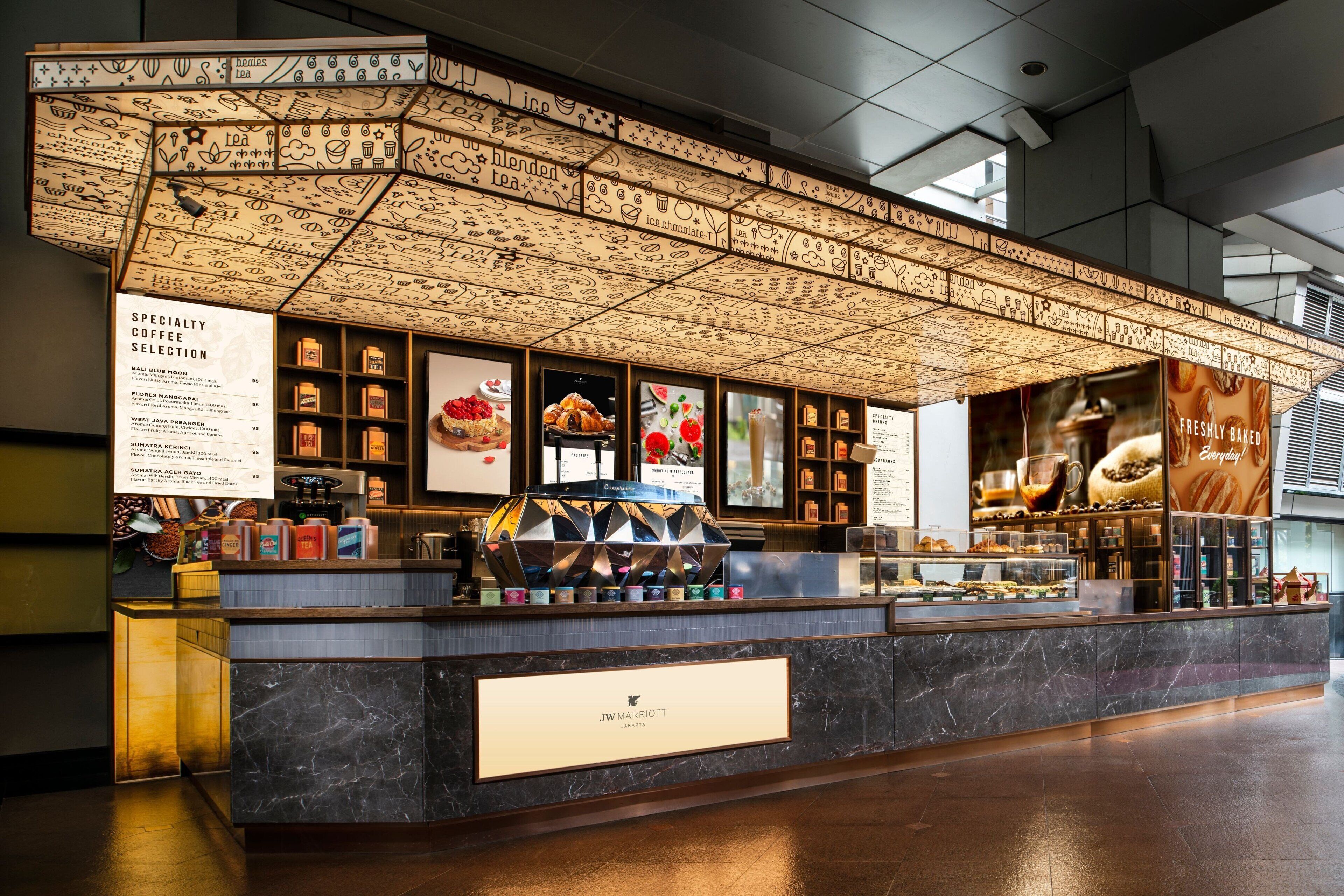 Una cafetería con una pizarra de menú, una variedad de granos de café y una exposición de pasteles.