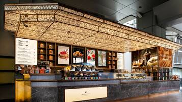 Una cafetería con una pizarra de menú, una variedad de granos de café y una exposición de pasteles.