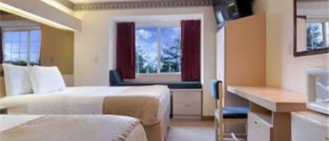 A hotel room with two beds, a desk, a chair, and a TV.