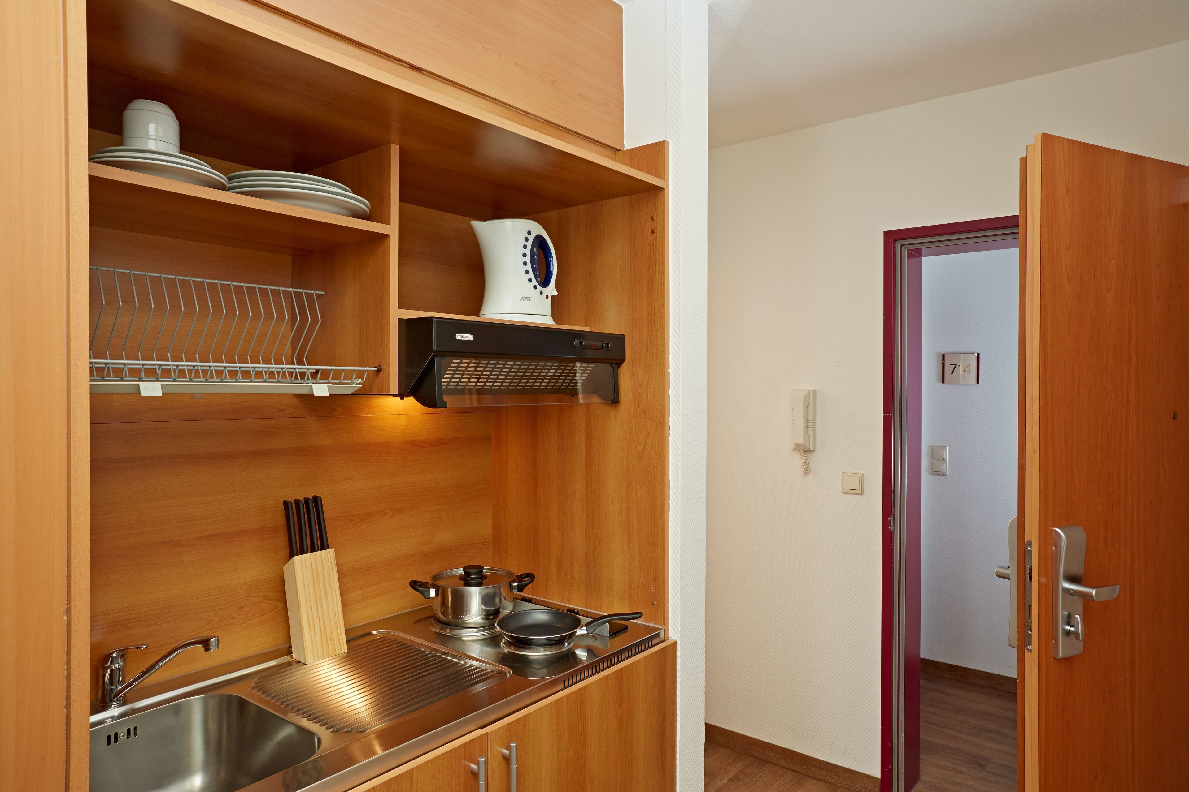Een kleine keuken met houten kastjes, een roestvrijstalen spoelbak en een inbouwfornuis.