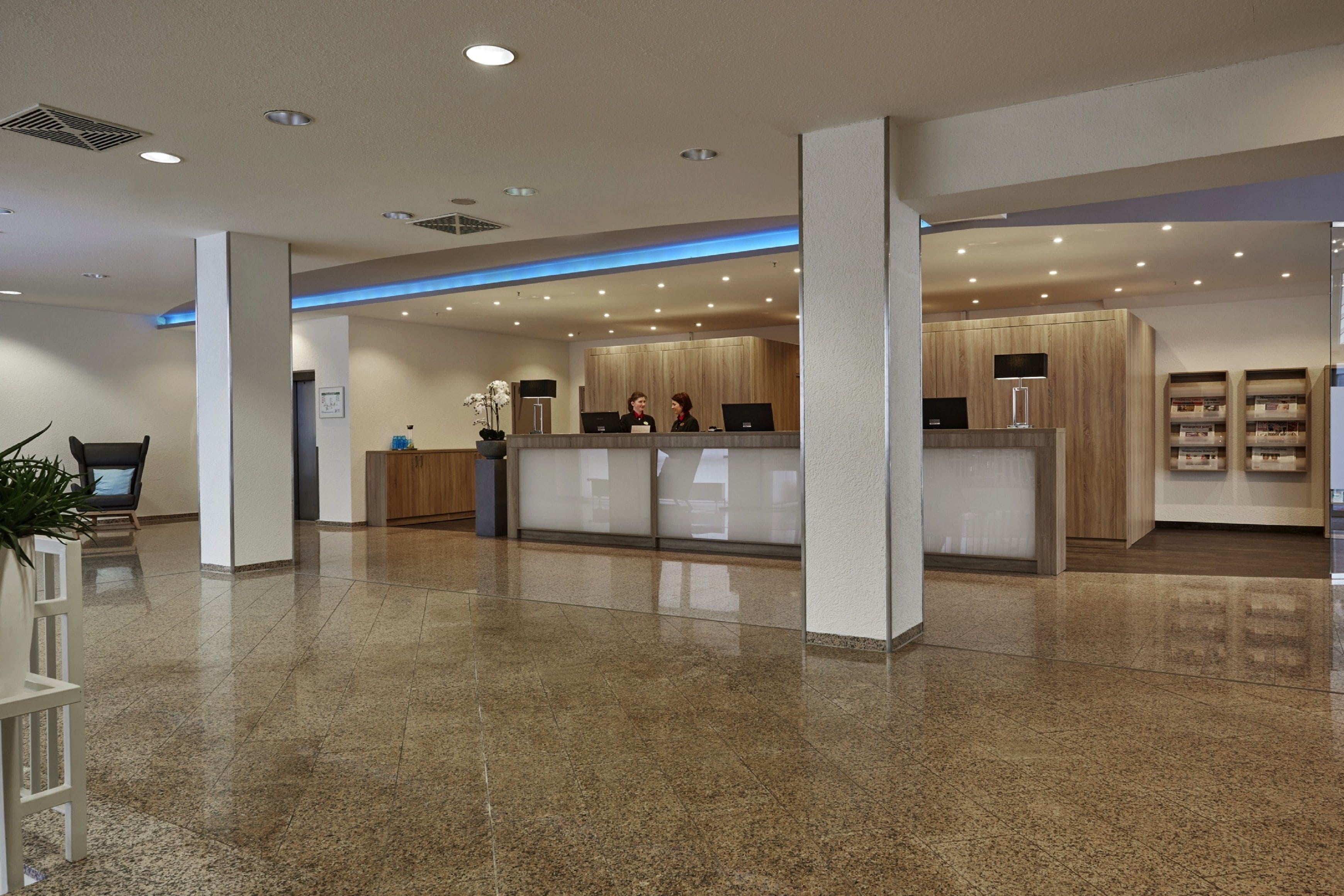 Uma área de recepção moderna com piso lustroso, balcão de atendimento e espaço de espera com planta.