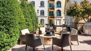 An outdoor patio with wicker furniture, a round table, and a grill area. - Residence Inn by Marriott Springfield (Springfield)