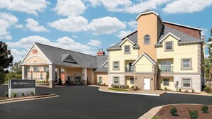 A multi-story hotel with a central entrance, a sign indicating it's a Marriott property, and a landscaped driveway.
