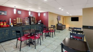 Un restaurant avec un comptoir, des chaises rouges et des tables.