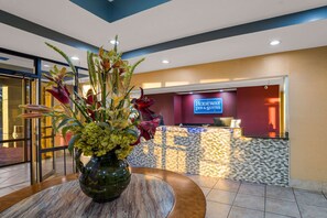 A reception area with a vase of flowers, a reception desk, and a sign for Rodeway Inn & Suites.