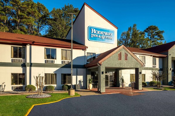 A Rodeway Inn & Suites building with a covered entrance, large windows, and a landscaped front yard.