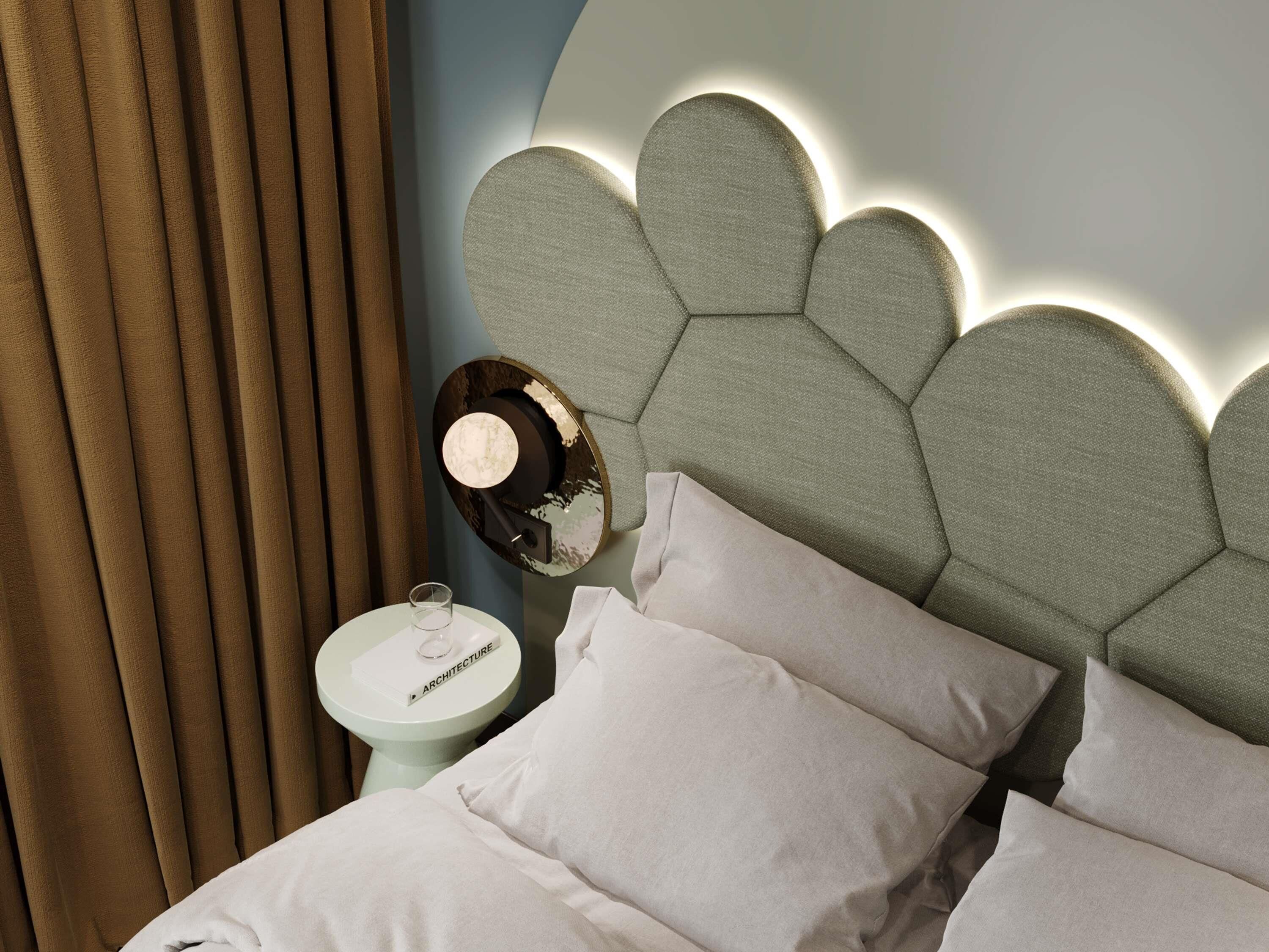 A bedroom with a bed, pillows, a bedside table with a lamp, and a wall-mounted light fixture.
