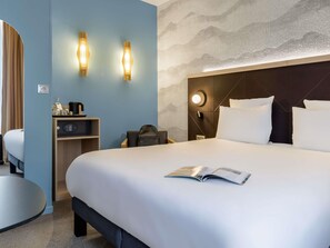 Une chambre d’hôtel comprenant un lit, une table de chevet, une lampe et un mur au décor texturé.