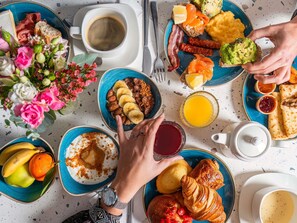 Un desayuno con diferentes opciones de comida, como tostadas, huevos, tocino y bollería.