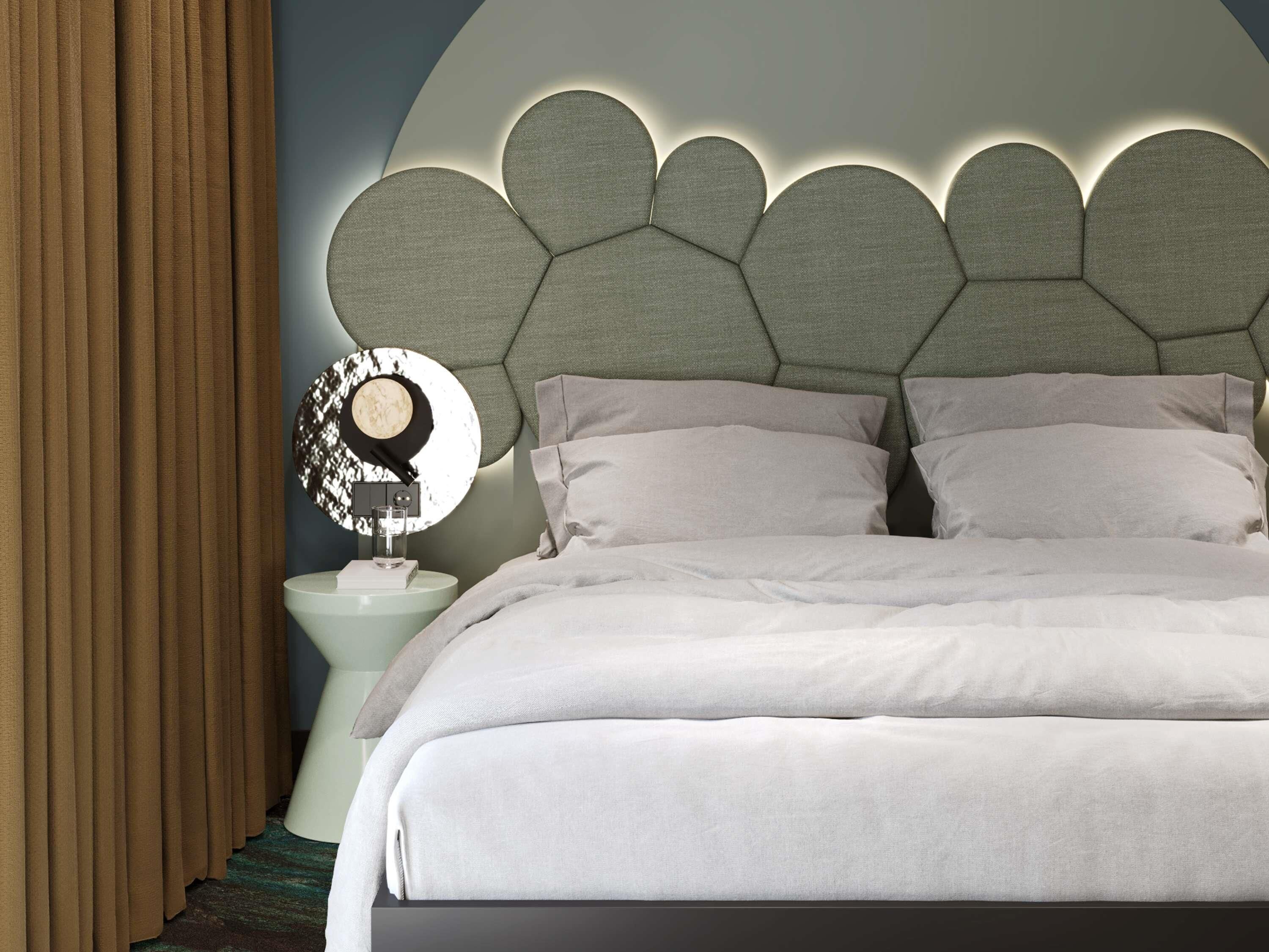 Un dormitorio con cama, almohadas, mesita de noche, lámpara y espejo adosado a la pared.