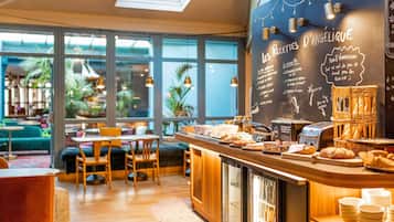 A café interior with a chalkboard menu, seating area, and a counter with food items.