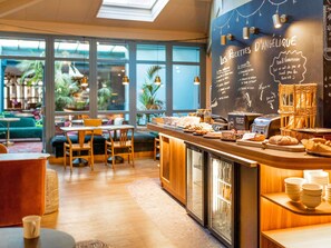 A café interior with a chalkboard menu, seating area, and a counter with food items. - ibis Styles Saint Étienne Gare Châteaucreux (Saint-Etienne)