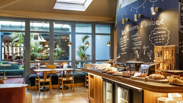 A café with a chalkboard menu, wooden furniture, and large windows. - ibis Styles Saint Étienne Gare Châteaucreux (Saint-Etienne)