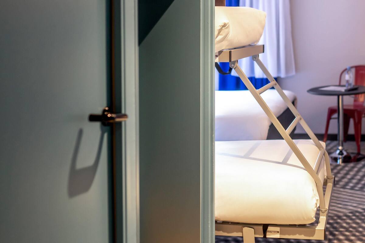 A hotel room with a bed, a chair, and a small table.