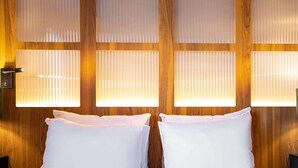 A hotel room with a wooden wall, two white pillows, and a bed. - ibis Styles Saint Étienne Gare Châteaucreux (Saint-Etienne)
