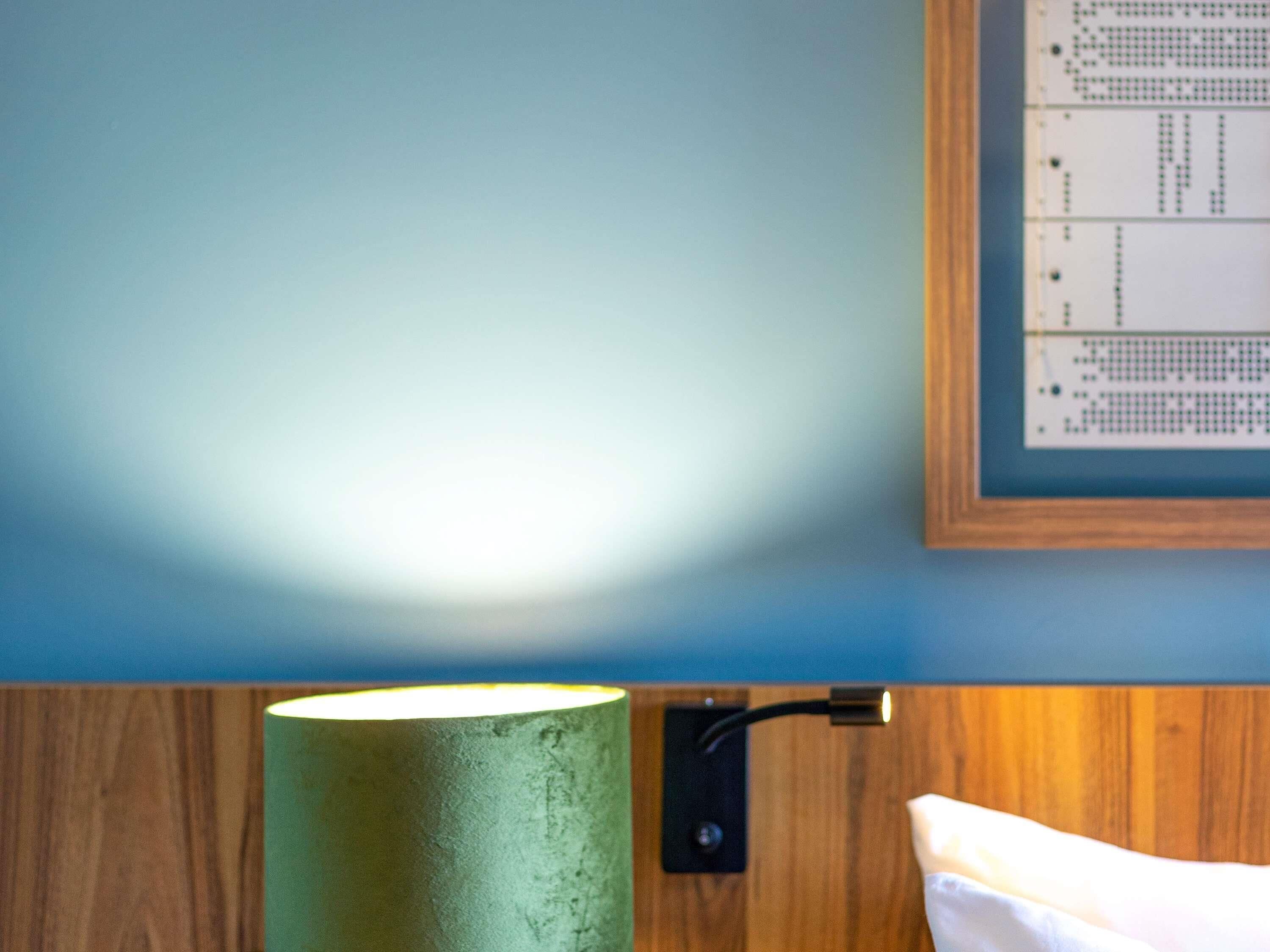 A room with a wooden wall, a framed picture, and a green cylindrical object.