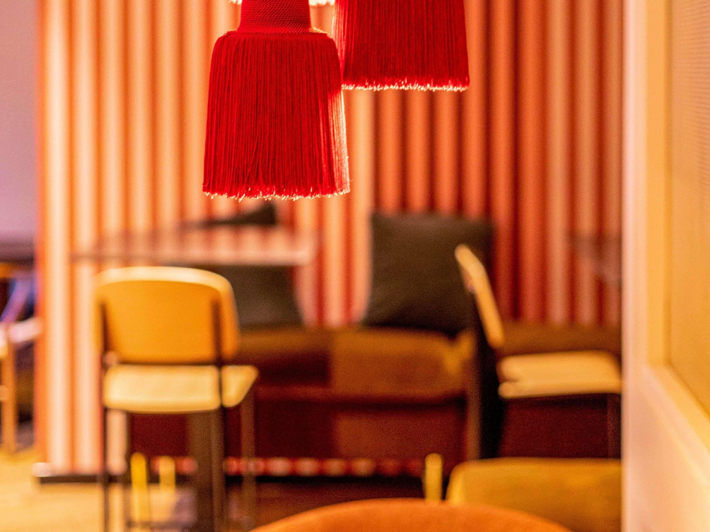Una habitación con pared a rayas, un sillón amarillo y una lámpara colgante roja.