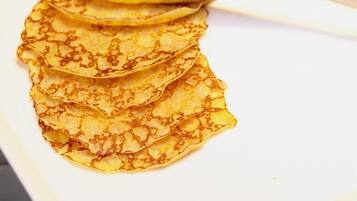 A stack of thin, golden-brown pancakes on a white plate.