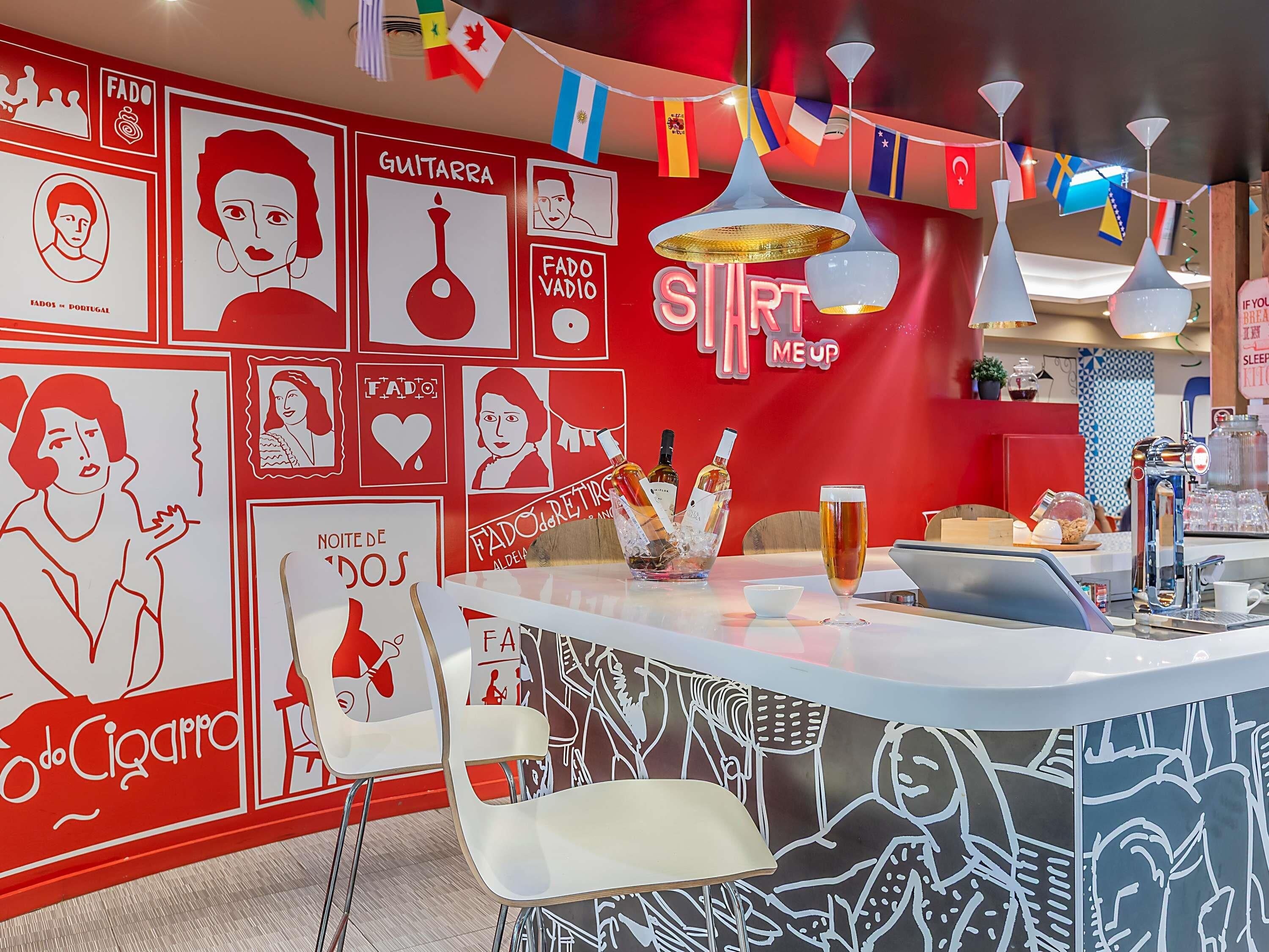 A bar area with a red and white color scheme, featuring a counter with a drink, a coffee machine, and a sign that reads 'SLEEP ME UP'.