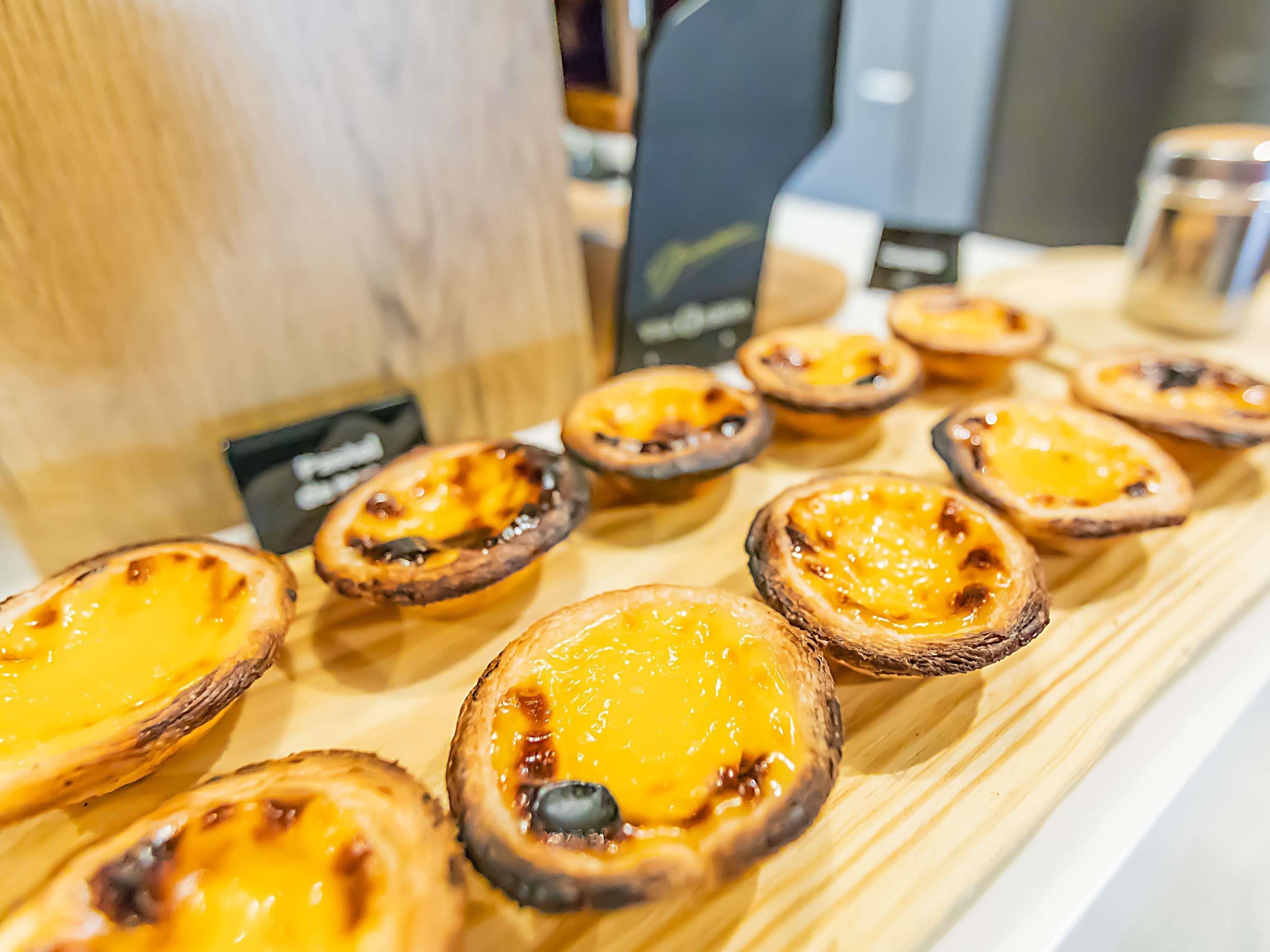 A display of Portuguese custard tarts on a wooden board.