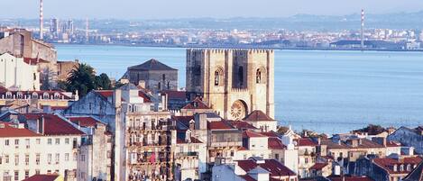 A coastal cityscape with historic buildings and a prominent tower by the waterfront.