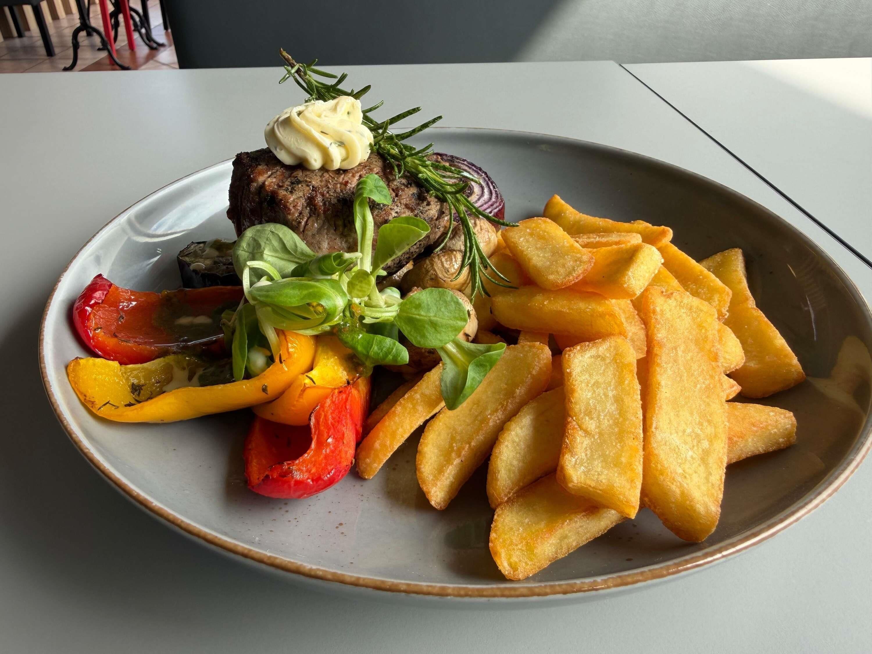 A plate with a steak, vegetables, and fries.