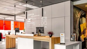 A hotel reception desk with a modern design, including a wooden counter and white panels.