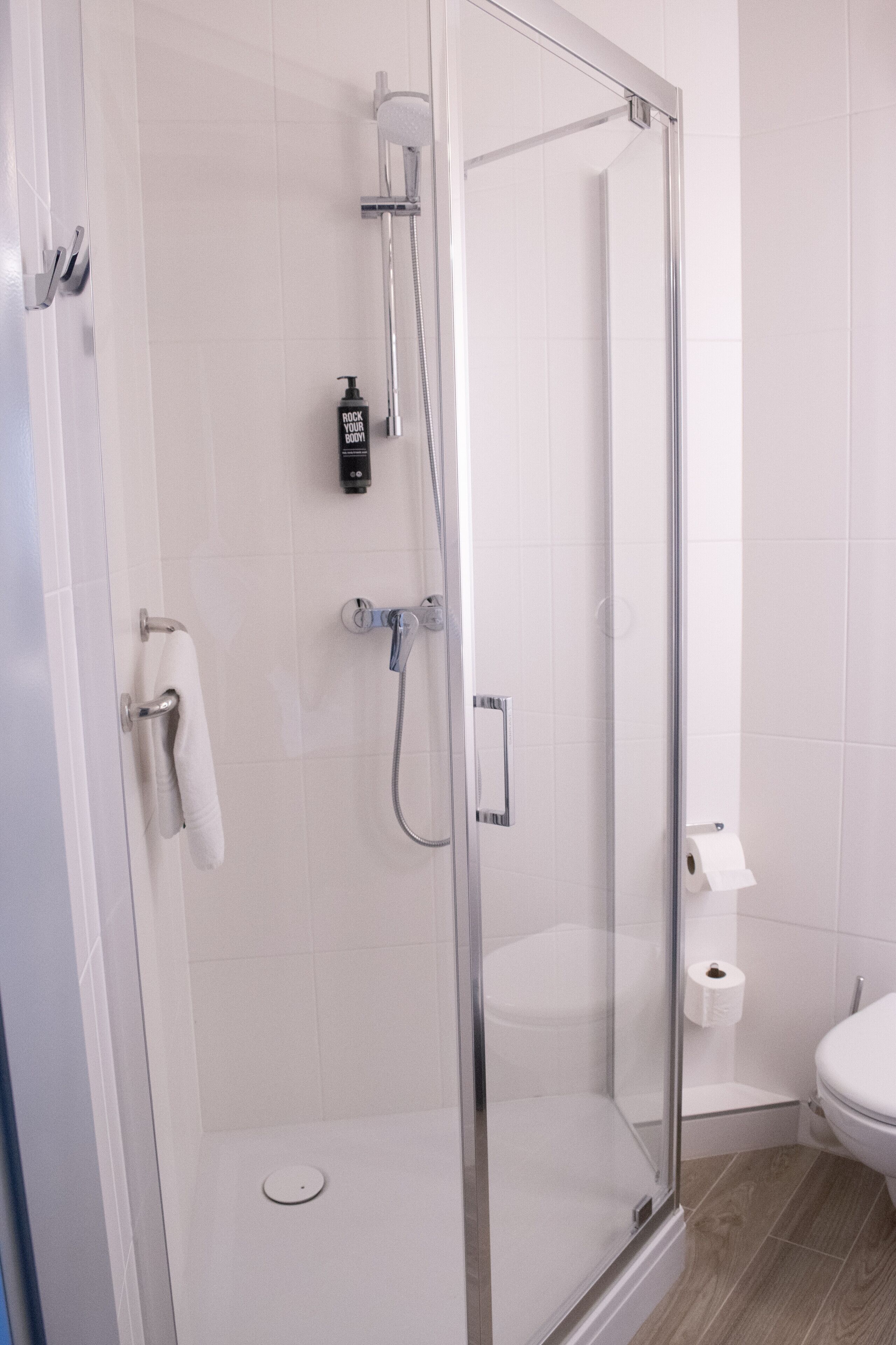 A modern bathroom with a glass-enclosed shower, a toilet, and a sink.