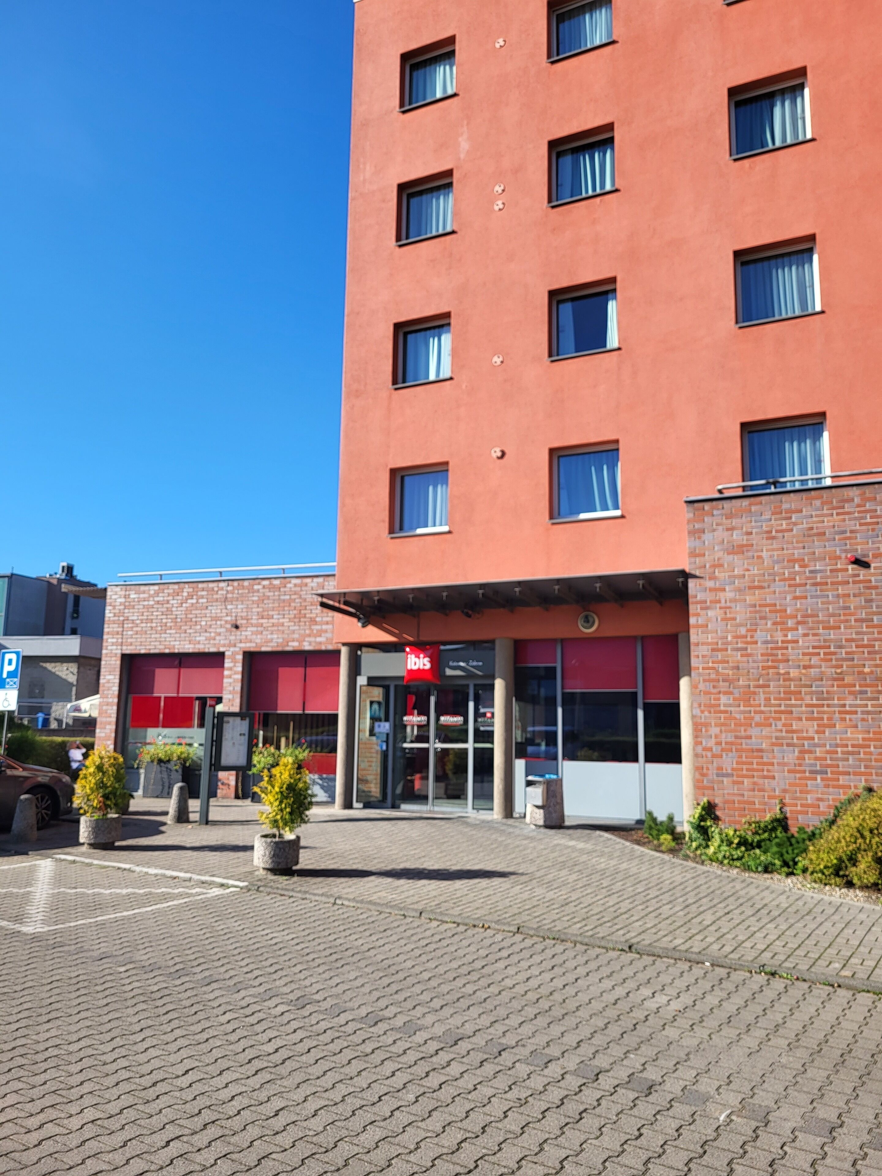 Ett hotell byggt av rött tegel, med ett rött markis och en parkeringsskylt med bokstaven ”P”.