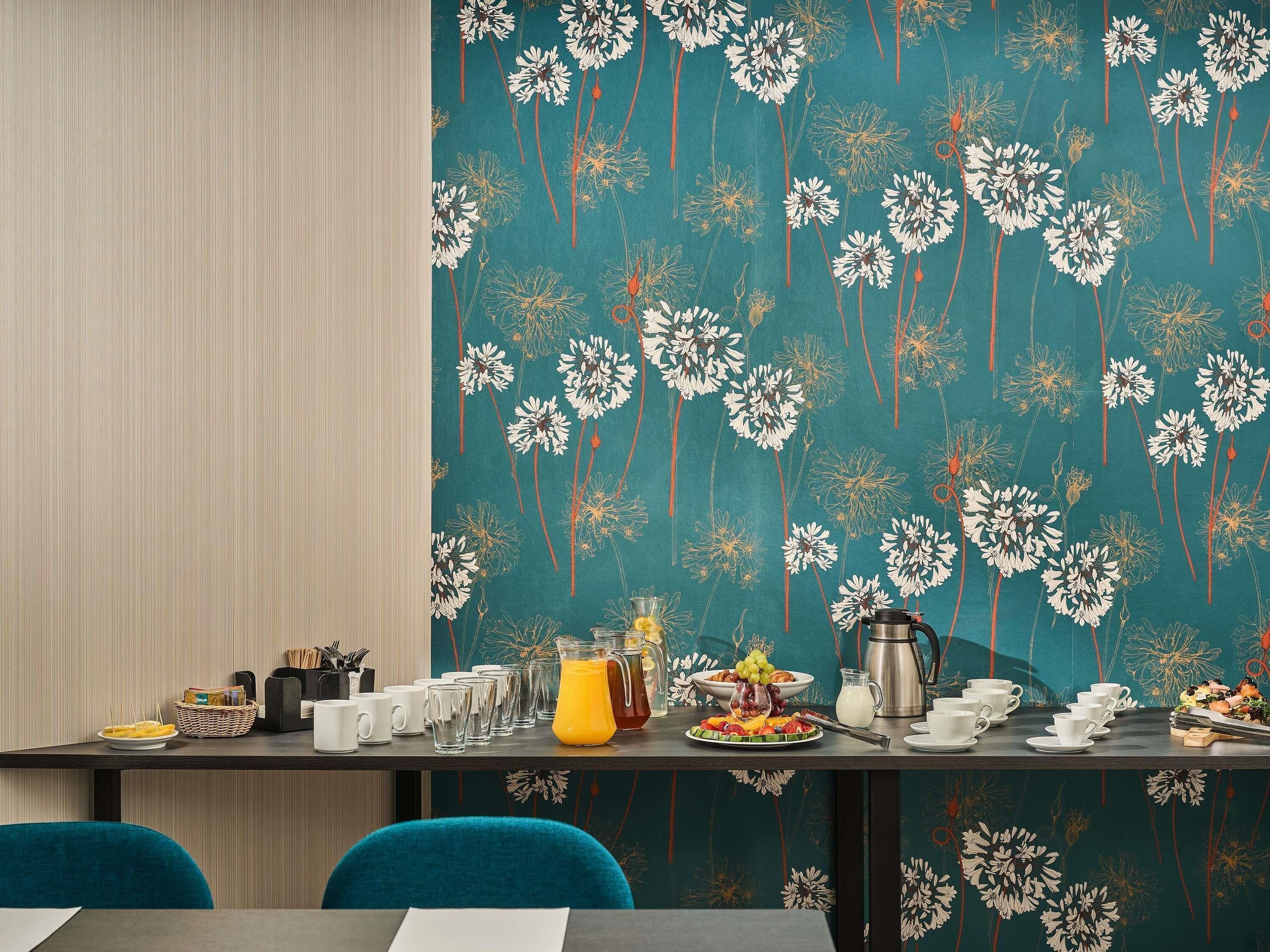A dining area with a table set for breakfast, including plates, cups, and a coffee pot.