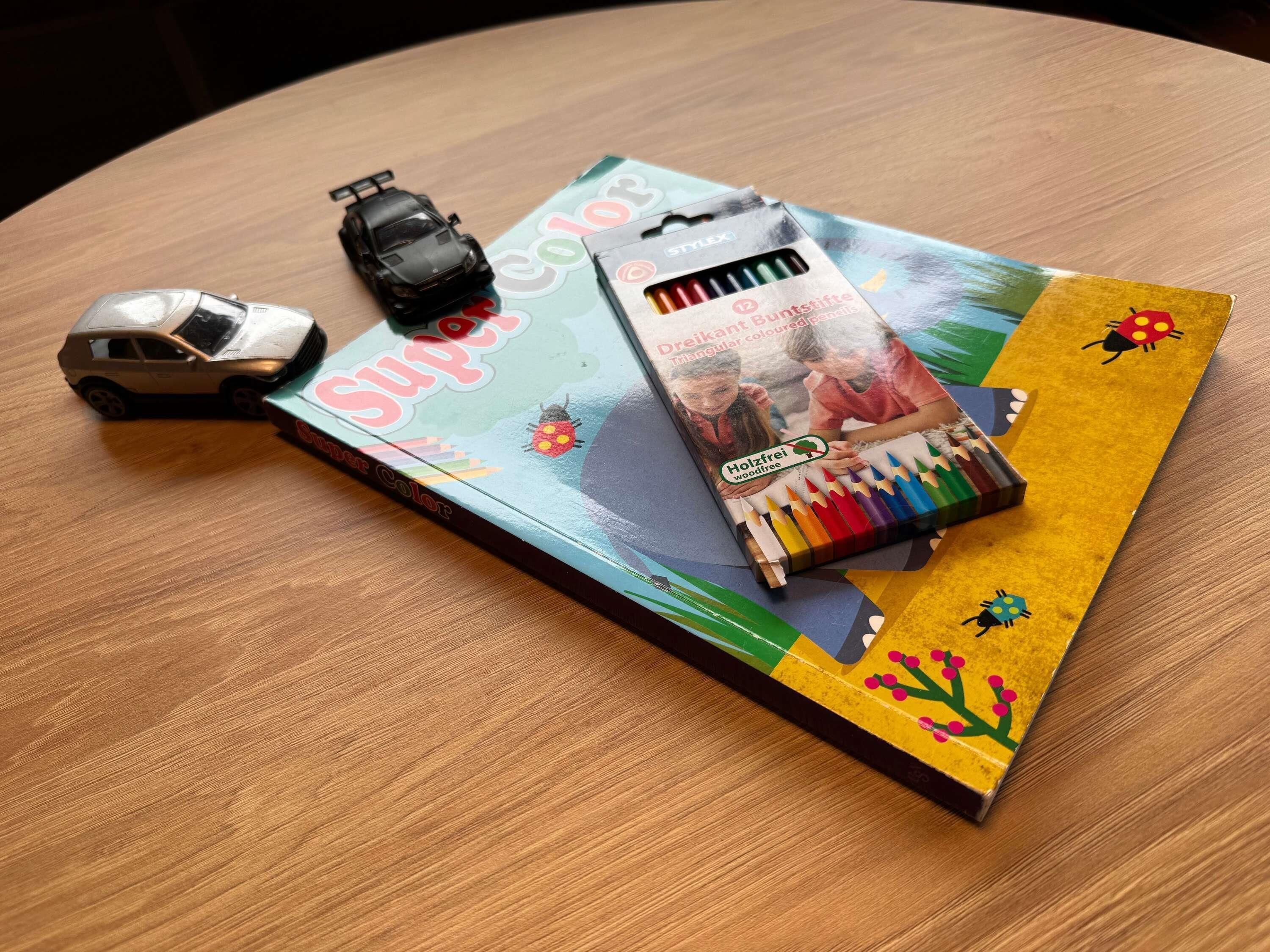 A table with a book, a toy car, and a set of colored pencils.