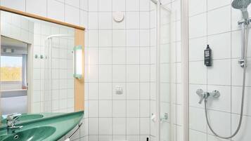 Un baño con un lavabo verde, un inodoro blanco, una ducha con cabezal de ducha manual y un espejo con marco de madera.