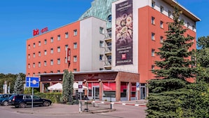 A hotel with a red facade, multiple windows, and a large banner advertising food services.