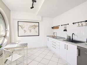 Una cocina moderna con armarios blancos, un lavamanos negro y un mapa mundial en la pared.