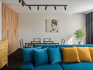 Una sala de estar moderna con un sofá, una mesa de comedor con sillas, un armario de madera y una planta en maceta.