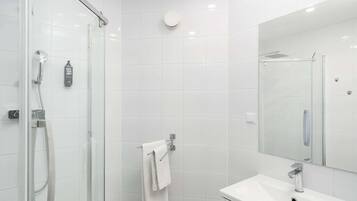 A modern bathroom with a glass shower enclosure, a white sink, and a large mirror.