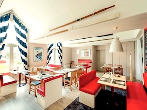 A modern restaurant with wooden furniture, red seating, and nautical-themed decor.
