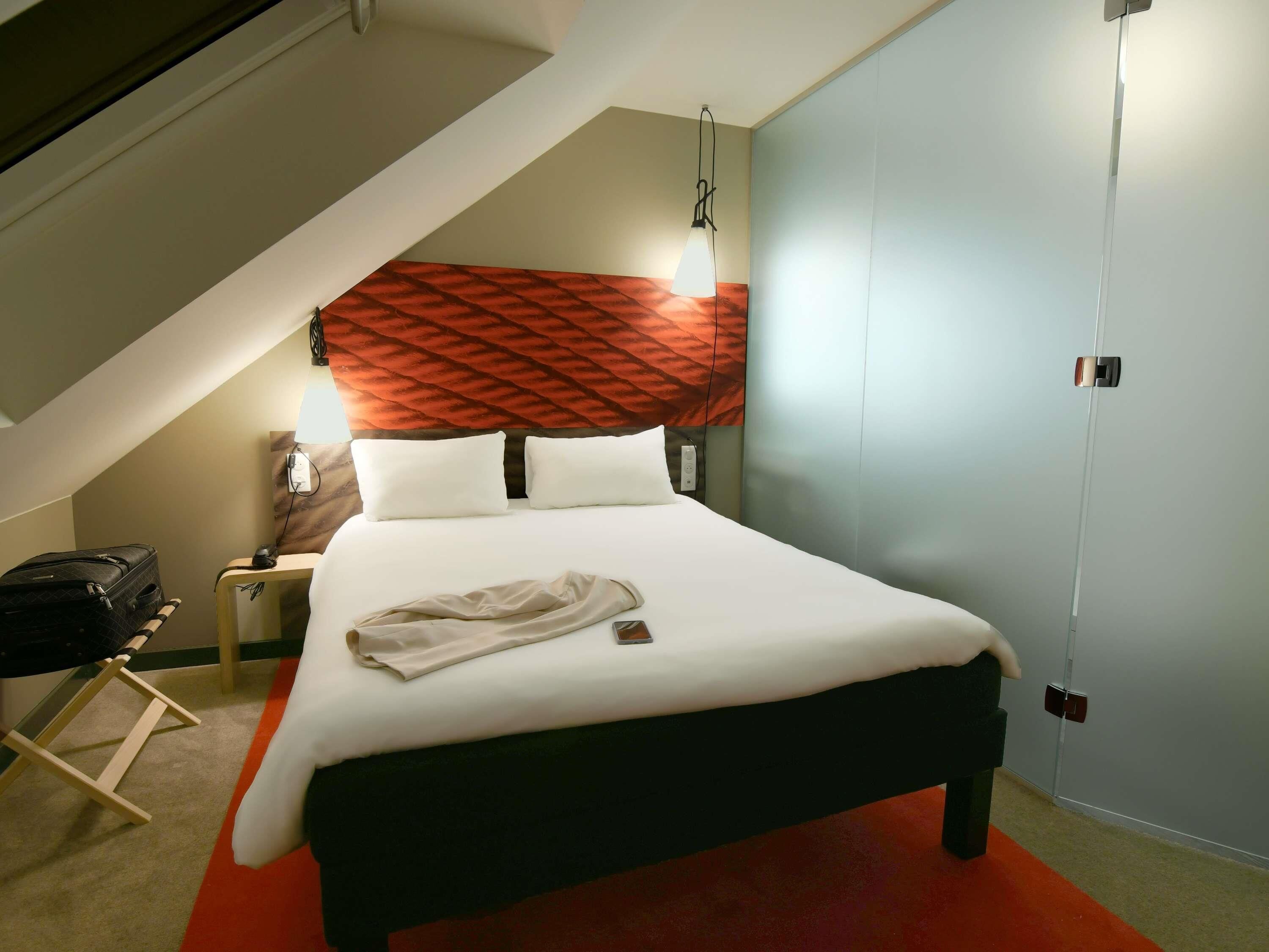 Una cama bien hecha con sábanas blancas, un cabecero rojo y un corredor de alfombra rojo.