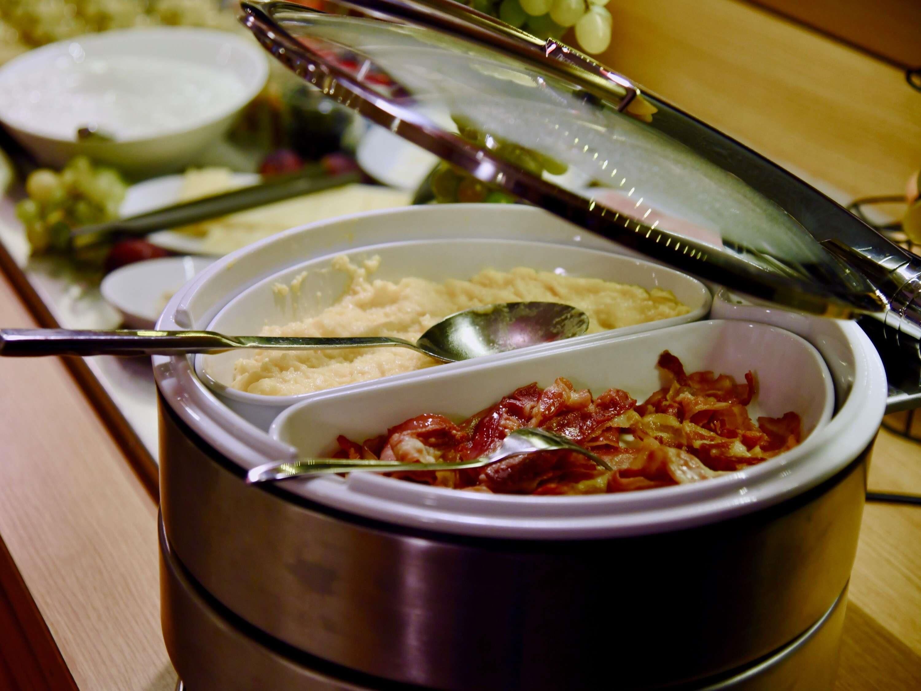 Mostra de buffet amb diversos plats, incloent un bol de puré de patates i un plat amb bacon.