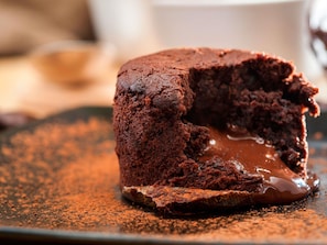 A chocolate lava cake with a gooey center and a dusting of cocoa powder on a plate. - ibis Manchester Centre Princess Street (Manchester)
