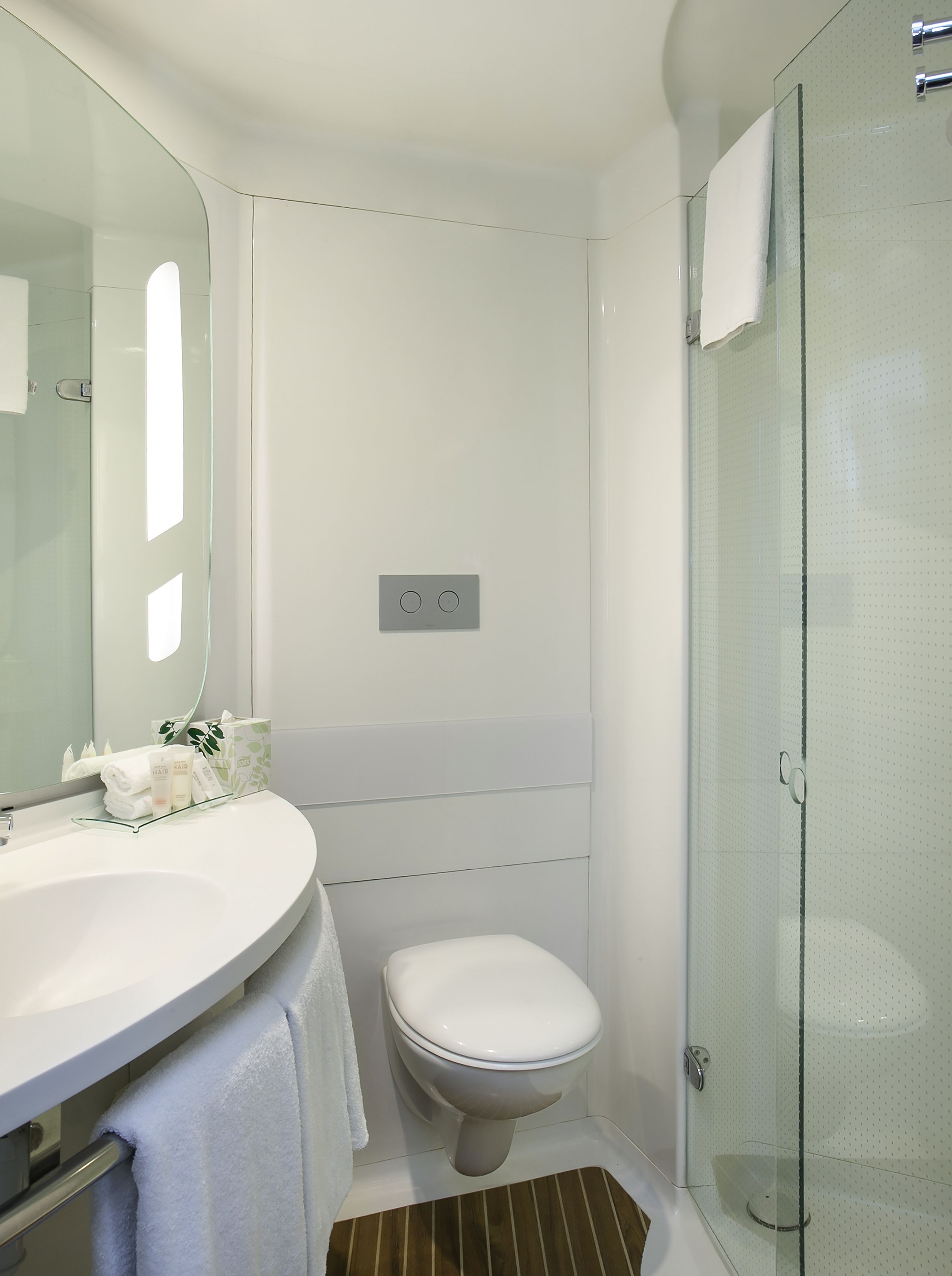 Ein modernes Badezimmer mit einem weißen Waschbecken, einer Toilette und einer Duschkabine aus Glas.