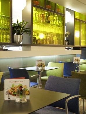 L’intérieur d’un restaurant, avec un bar, des tables et des chaises, et un panneau affichant le menu.