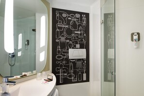 Une salle de bain moderne avec un grand miroir, un lavabo blanc et un mur noir orné d’icônes blanches sur le thème de la salle de bain.