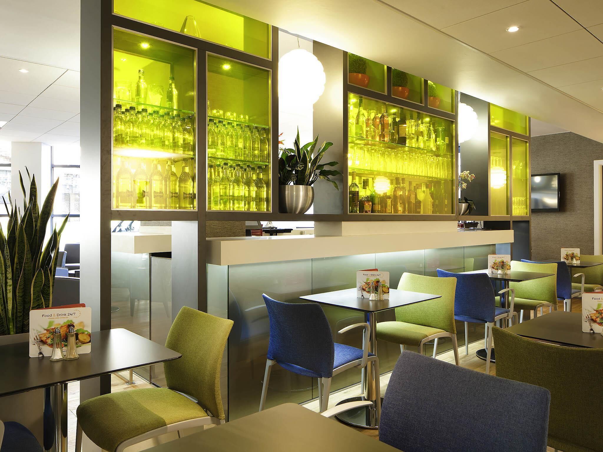 A modern restaurant interior with a bar area, seating, and a menu stand.