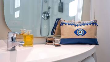 Un lavamanos con espejo, una botella de perfume, un espejo de bolsillo y una toalla decorativa.