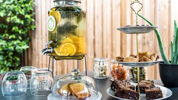 Un dispensador de bebidas con tapa de vidrio, un expositor escalonado para postres con brownies, y una claraboya de cristal sobre una bandeja de pasteles.